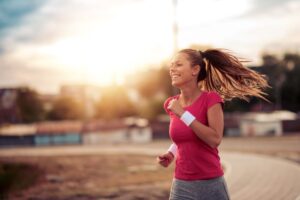 Fit woman smiling as she jogs outdoors