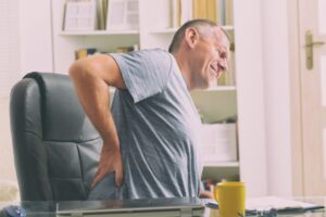 Man sitting at desk, dealing with back pain